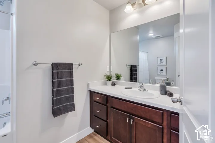 Bathroom featuring a single vanity with a white countertop, dark wood-finish cabinetry, an undermount sink, and chrome fixtures