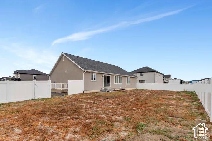 Expansive yard space featuring a full perimeter fence, concrete patio, and rear entry access