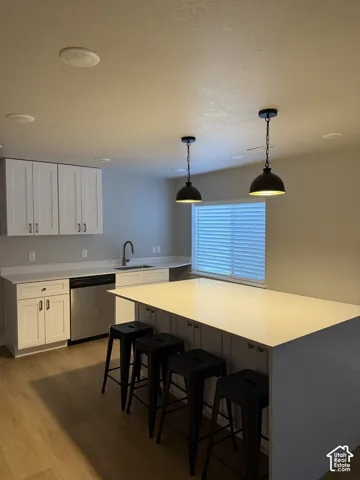 White shaker-style cabinetry with stainless steel appliances, light-toned countertops, wood-finish flooring, and recessed lighting