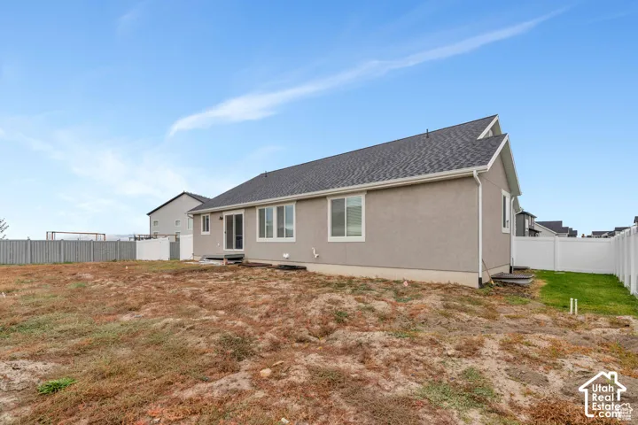 Exterior featuring a gray stucco finish, dark shingle roof, white vinyl windows, and a sliding glass door