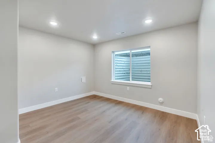 Recessed ceiling lighting, light gray wall finish, wood-finish flooring, white window trim, and white baseboards