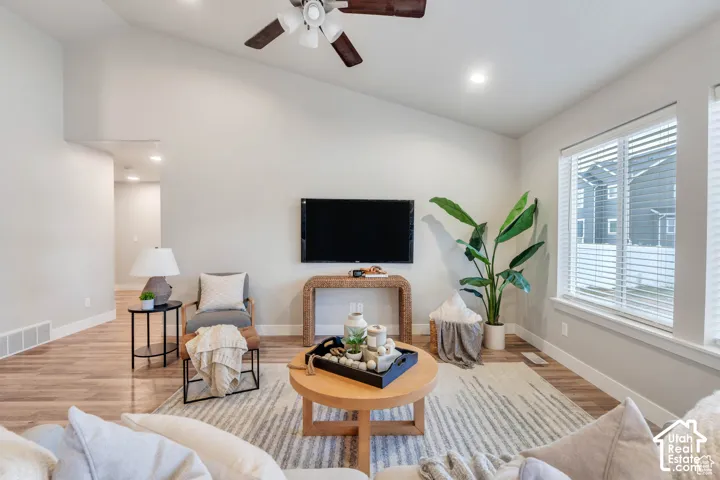 Vaulted ceiling with a ceiling fan, recessed lighting, wood-finish flooring, and white window blinds