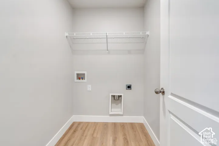 Utility area featuring wood-finish flooring, white wire shelving, and appliance hookups