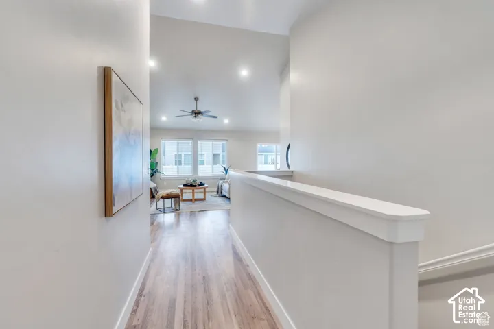 Hardwood-style flooring extends through the hallway, complemented by recessed lighting and a white wall railing