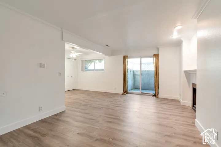 Wood-finish flooring throughout, white crown molding, recessed lighting, and a fireplace with a white mantel