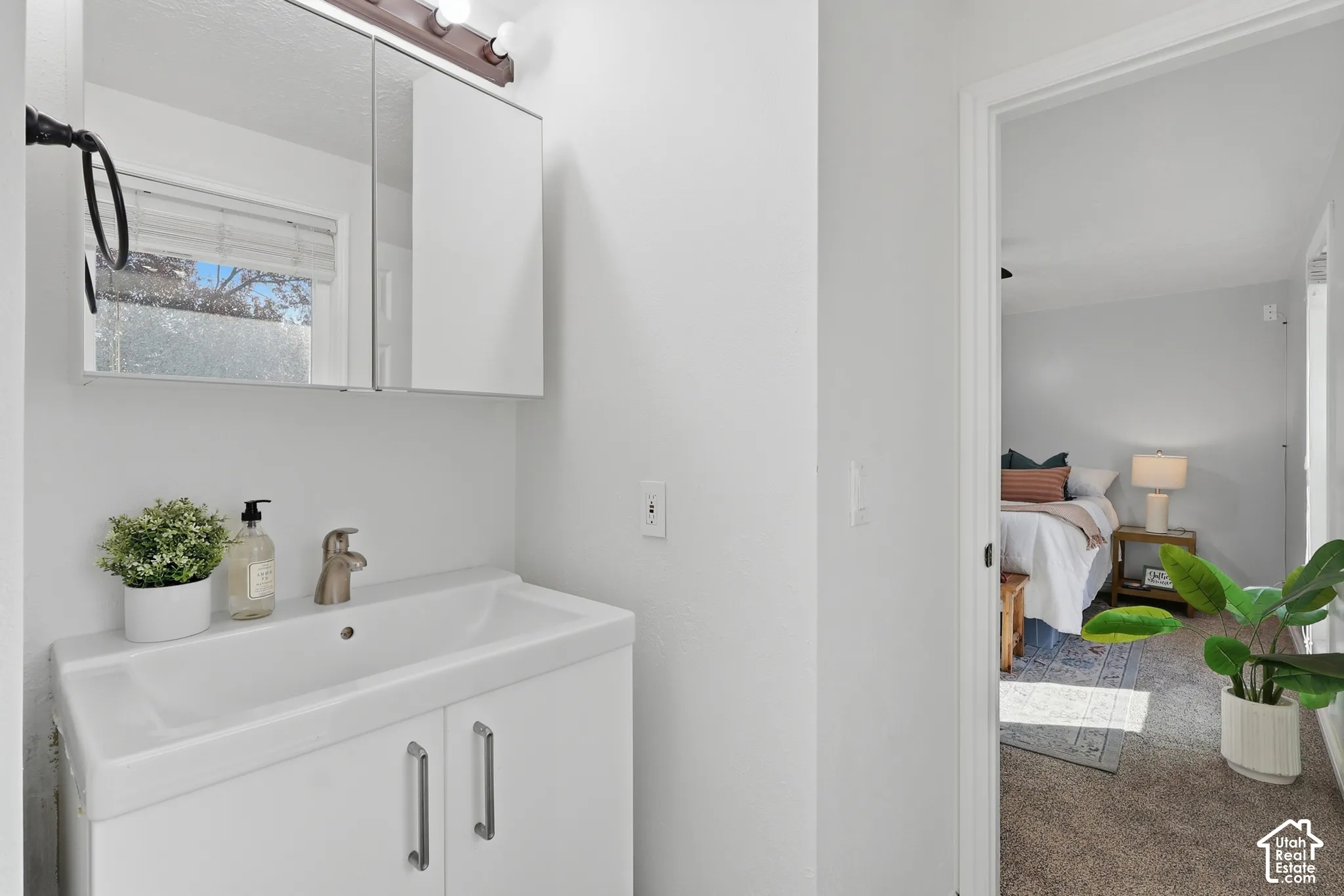 Bathroom vanity with a white ceramic sink and brushed nickel faucet, paired with a mirrored medicine cabinet and overhead lighting