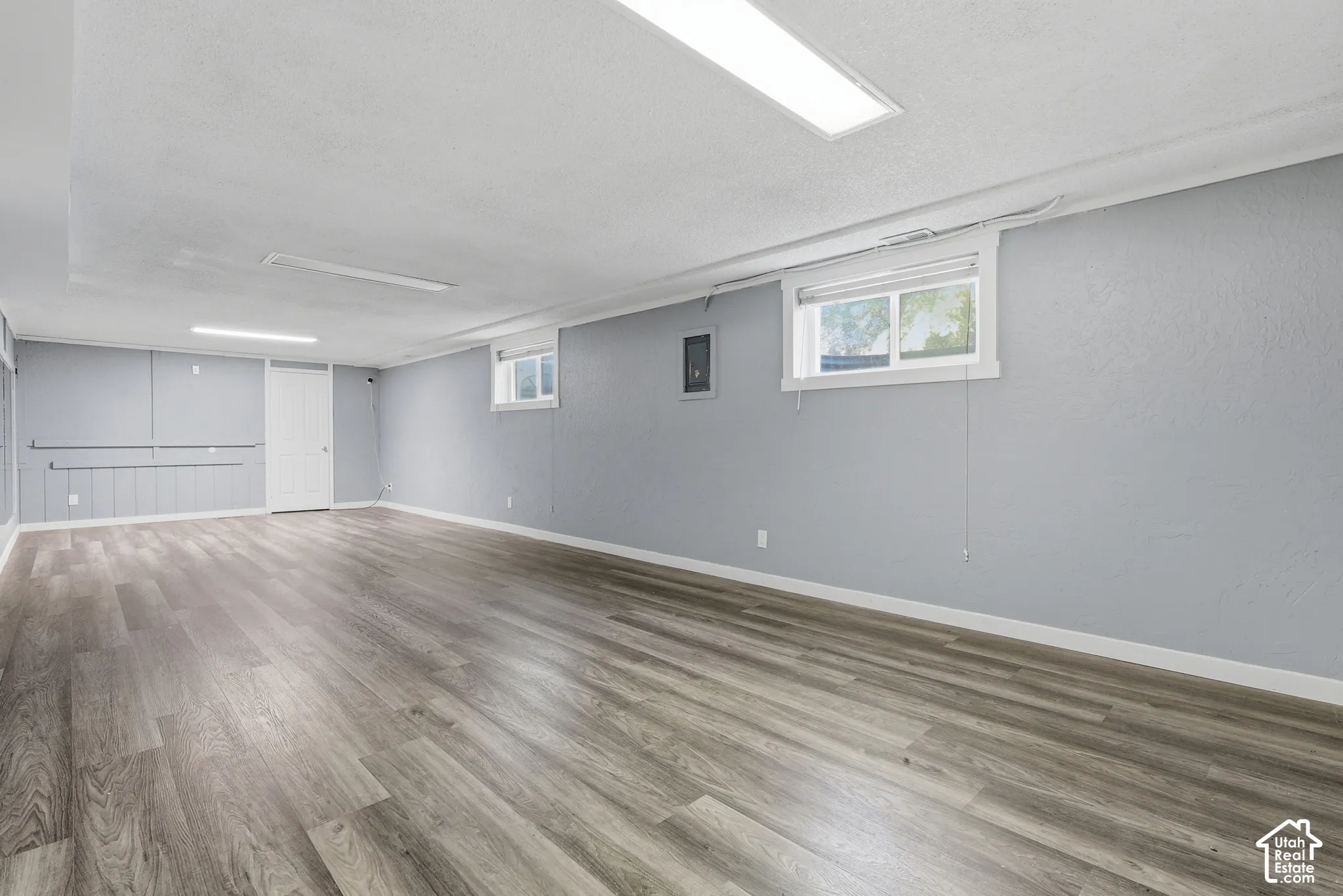Spacious room featuring wood-finish flooring, light gray walls, white trim, and recessed lighting fixtures