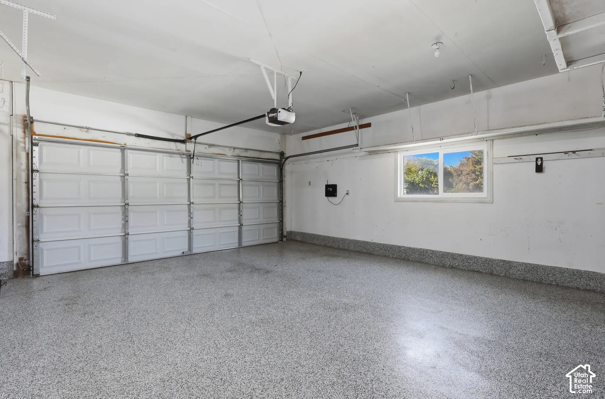 Spacious two-car garage featuring an epoxy-coated concrete floor, overhead garage door openers, and abundant natural light from transom windows