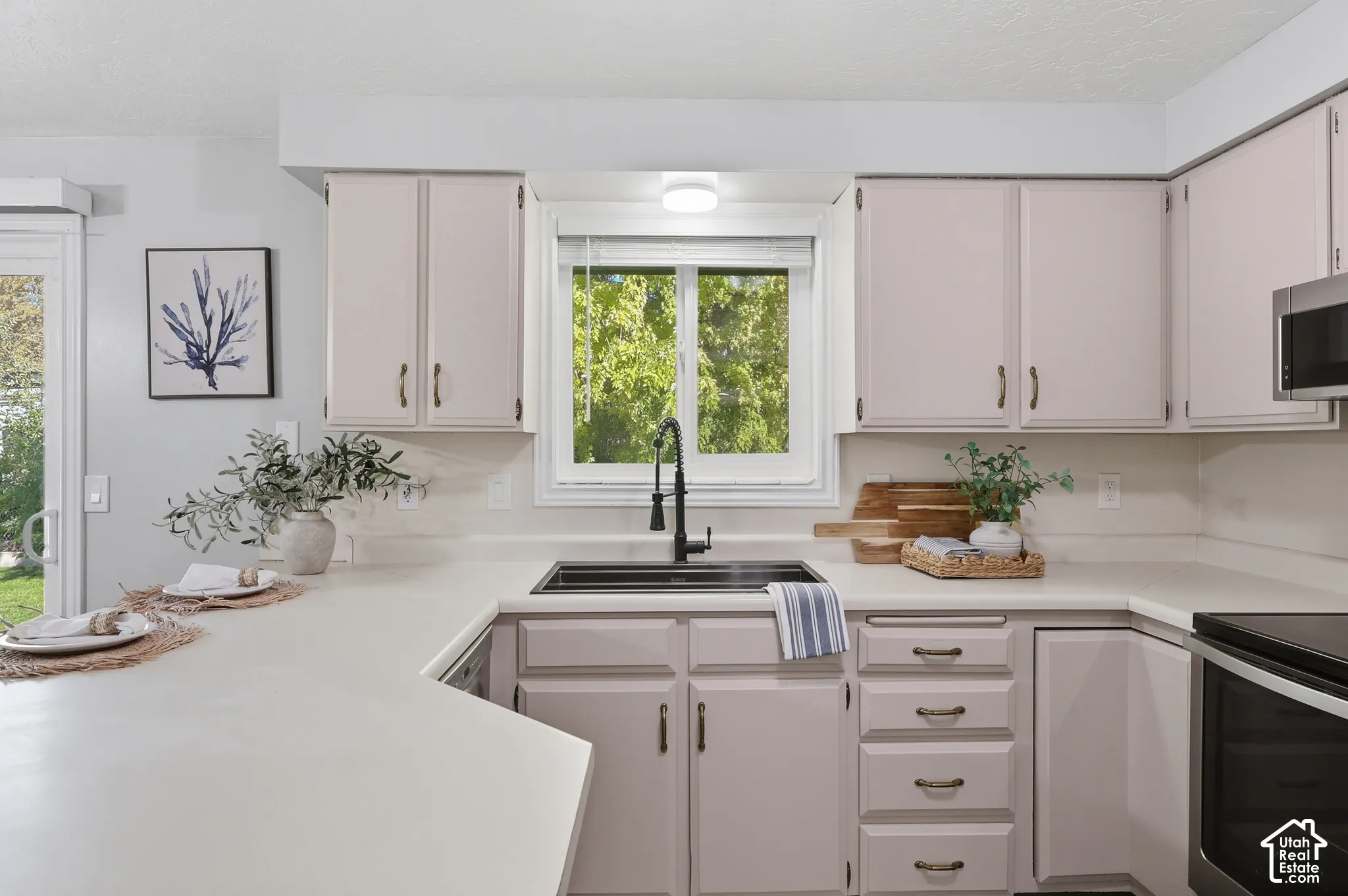 White cabinetry with dark hardware, a stainless steel sink with a matte black faucet, and a built-in microwave