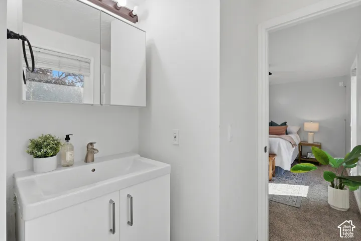 Bathroom vanity with a white ceramic sink and brushed nickel faucet, paired with a mirrored medicine cabinet and overhead lighting