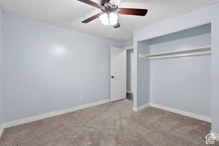 Gray carpet flooring, white trim, recessed closet, ceiling fan with integrated lighting, and a paneled door