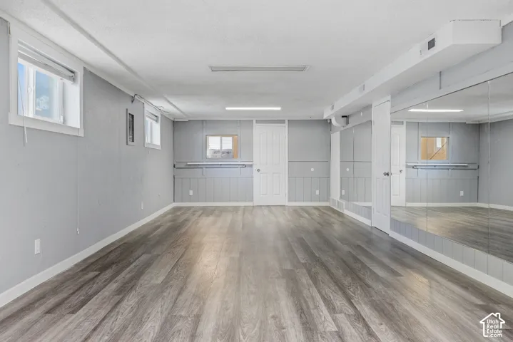 Spacious room with wood-finish flooring, full-wall mirror, two windows, and board and batten wall detailing