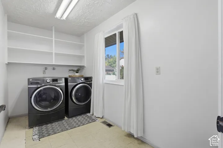 Laundry area featuring white walls, overhead shelving, and a window for natural light