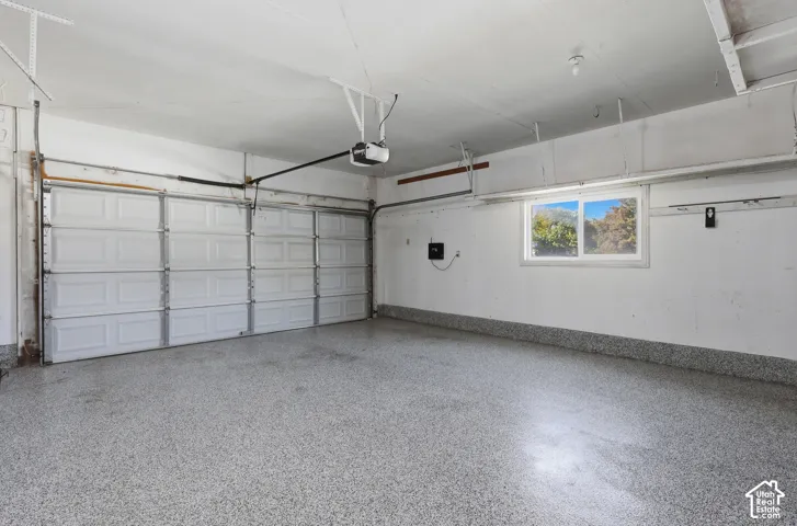 Spacious two-car garage featuring an epoxy-coated concrete floor, overhead garage door openers, and abundant natural light from transom windows
