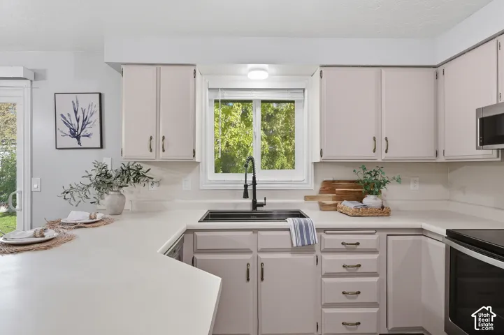 White cabinetry with dark hardware, a stainless steel sink with a matte black faucet, and a built-in microwave