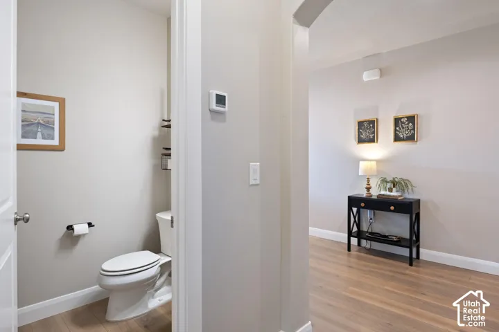 Powder room featuring wood-finish flooring and a toilet