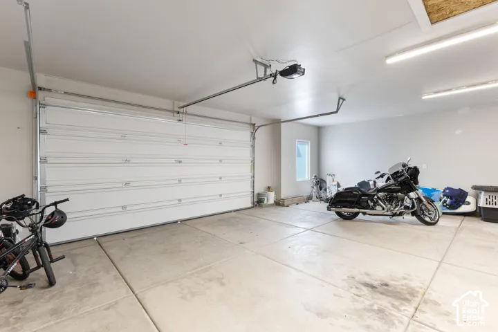 Garage space with a concrete floor, white walls, and overhead fluorescent lighting