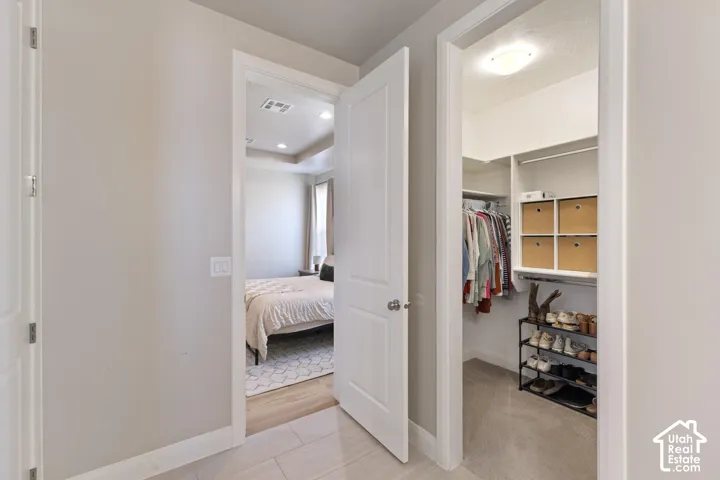 Bedroom featuring tray ceiling and recessed lighting, with a walk-in closet providing built-in shelving and ample storage