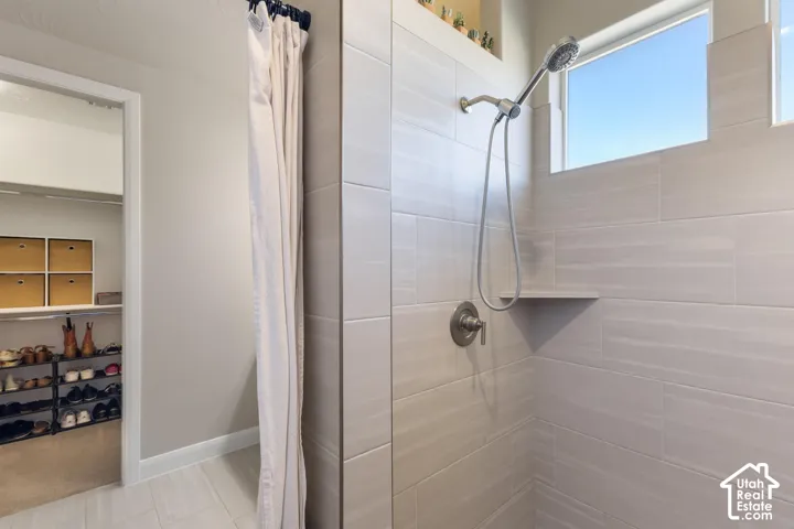 Tiled shower with handheld shower fixture, built-in shower shelf, and frosted window