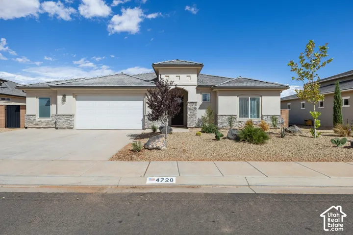 Stucco exterior with stone accents, a two-car garage, and a covered entry
