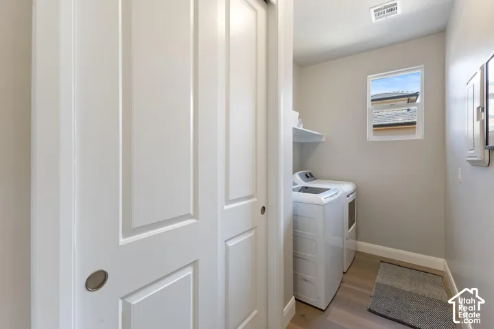 Laundry area featuring wood-finish flooring, a white floating shelf, and a window