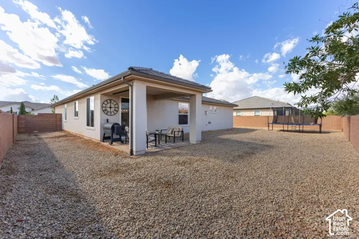 Expansive backyard featuring a covered patio, gravel landscaping, and perimeter fencing