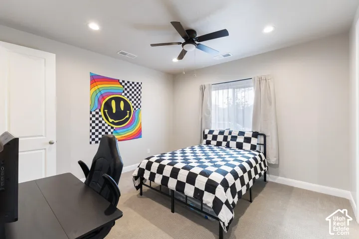Recessed ceiling lighting, ceiling fan, single window with roller blinds, light-toned wall paint, and neutral carpeting