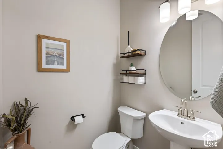 Pedestal sink with brushed nickel faucet, oval wall mirror, and modern vanity lighting