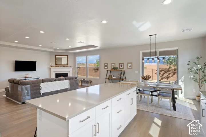 Spacious open-concept living area featuring wood-finish flooring, recessed lighting, and a fireplace with a mantel