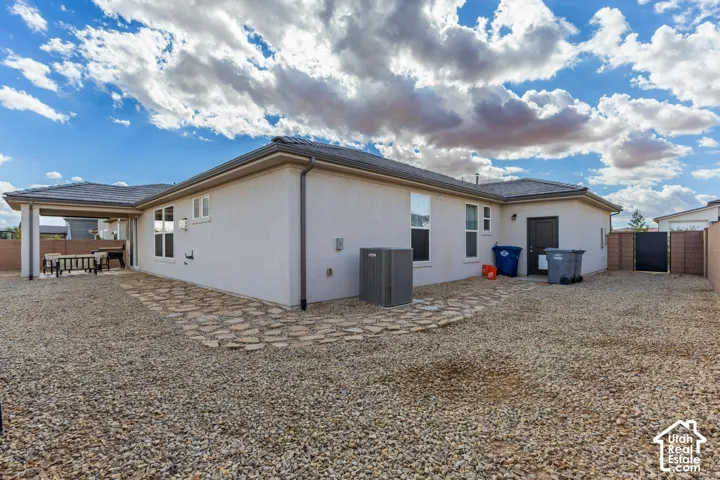 Stucco exterior with a covered patio, gravel landscaping, and a stone-paver walkway