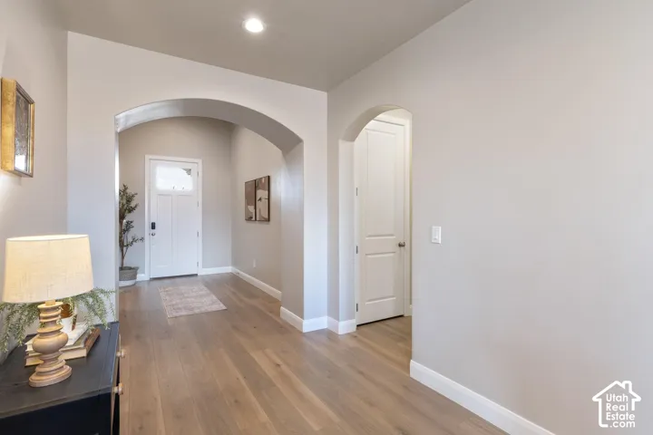 Wood-finish flooring throughout, featuring arched doorways and white trim