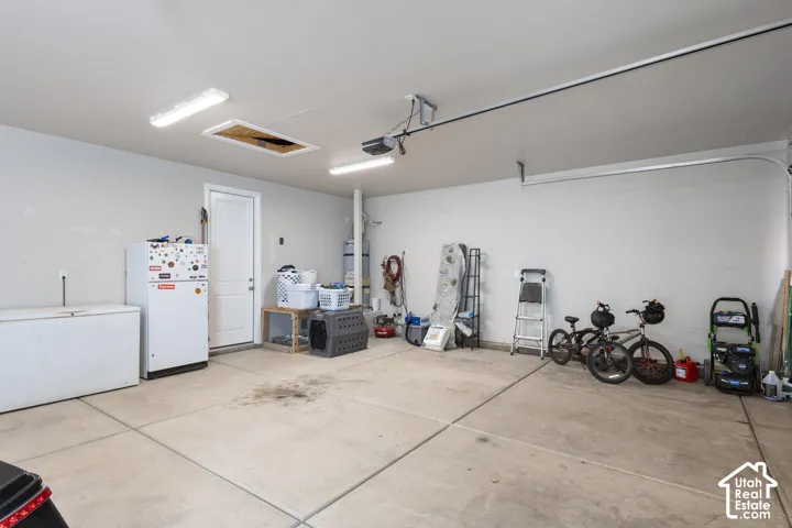 Attached two-car garage with concrete flooring, overhead lighting, and interior access door