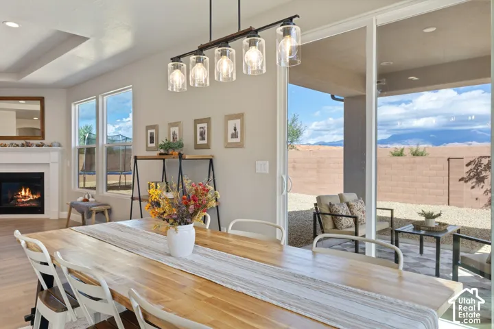 Recessed ceiling, wood-finish flooring, white fireplace with mantel, sliding glass door, and a covered patio