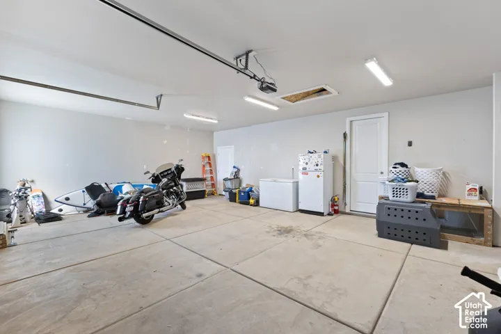 Spacious garage featuring concrete flooring, white walls, and overhead fluorescent lighting