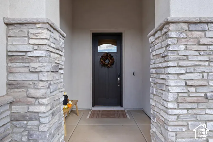Entryway featuring stacked stone columns, a dark wood-finish front door with an arched window, and concrete flooring