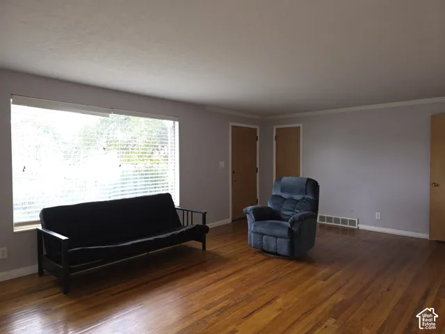 Spacious room featuring wood-finish flooring, a large picture window, and solid core doors