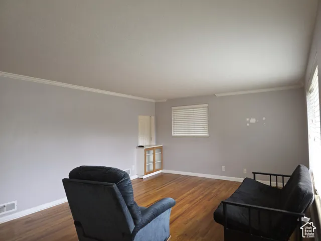Wood-finish flooring, neutral wall tones, built-in cabinetry with glass-front doors, and horizontal window blinds