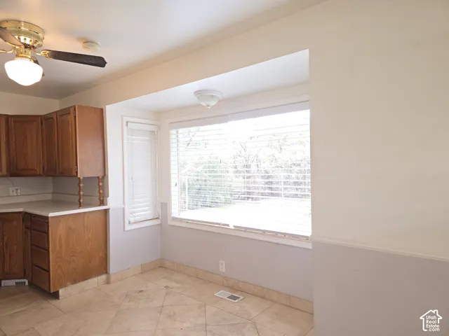 Kitchen featuring wood cabinetry, stone-finish tile flooring, recessed window bay, and ceiling-mounted light fixtures