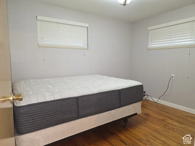Room featuring wood-finish flooring, neutral wall paint, and two windows equipped with horizontal blinds