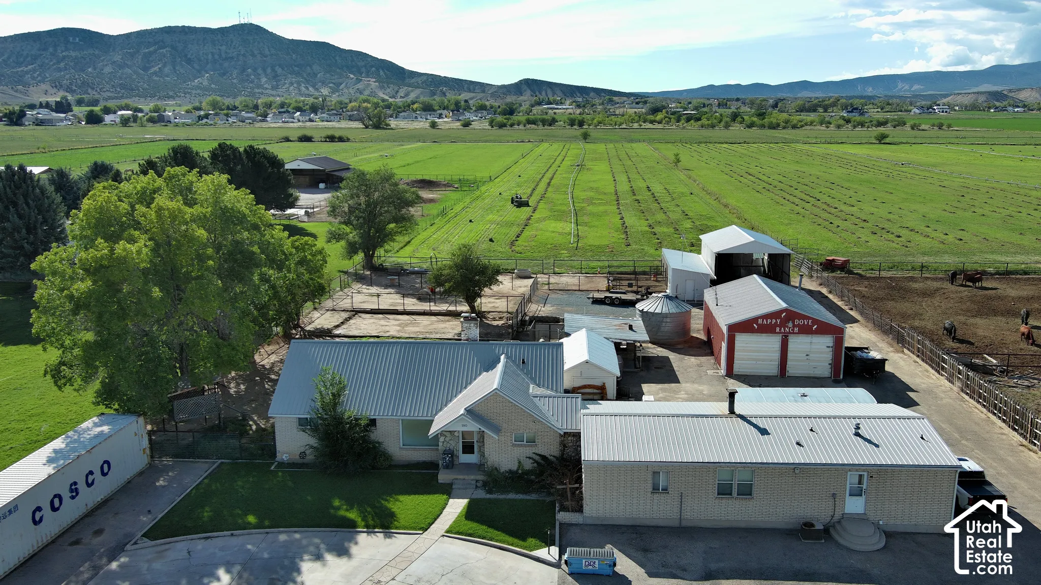 Expansive property featuring multiple structures, a red two-car garage, and a large fenced animal enclosure