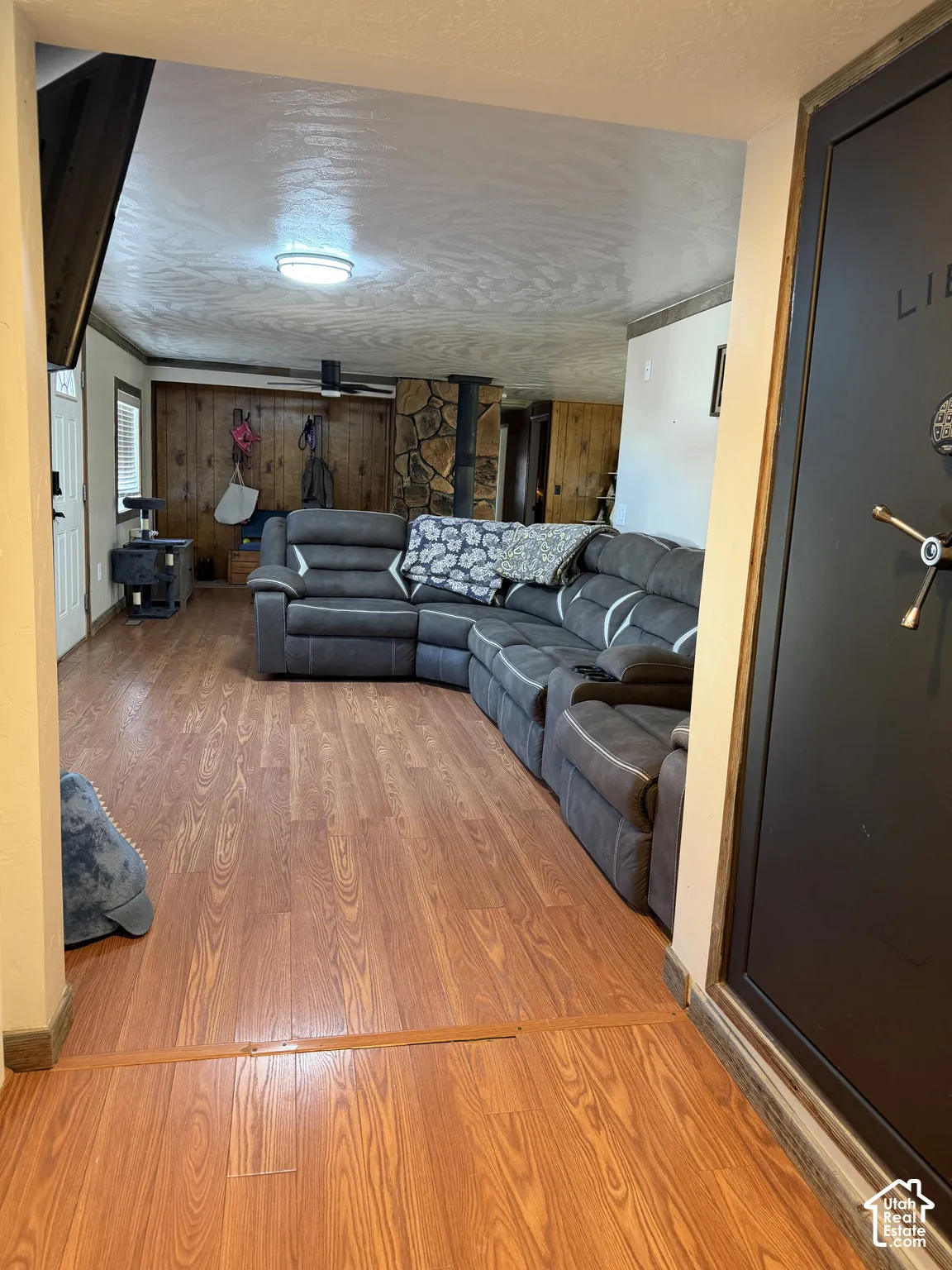 Wood-finish flooring throughout, featuring a stone-clad wood-burning stove, and wood paneling