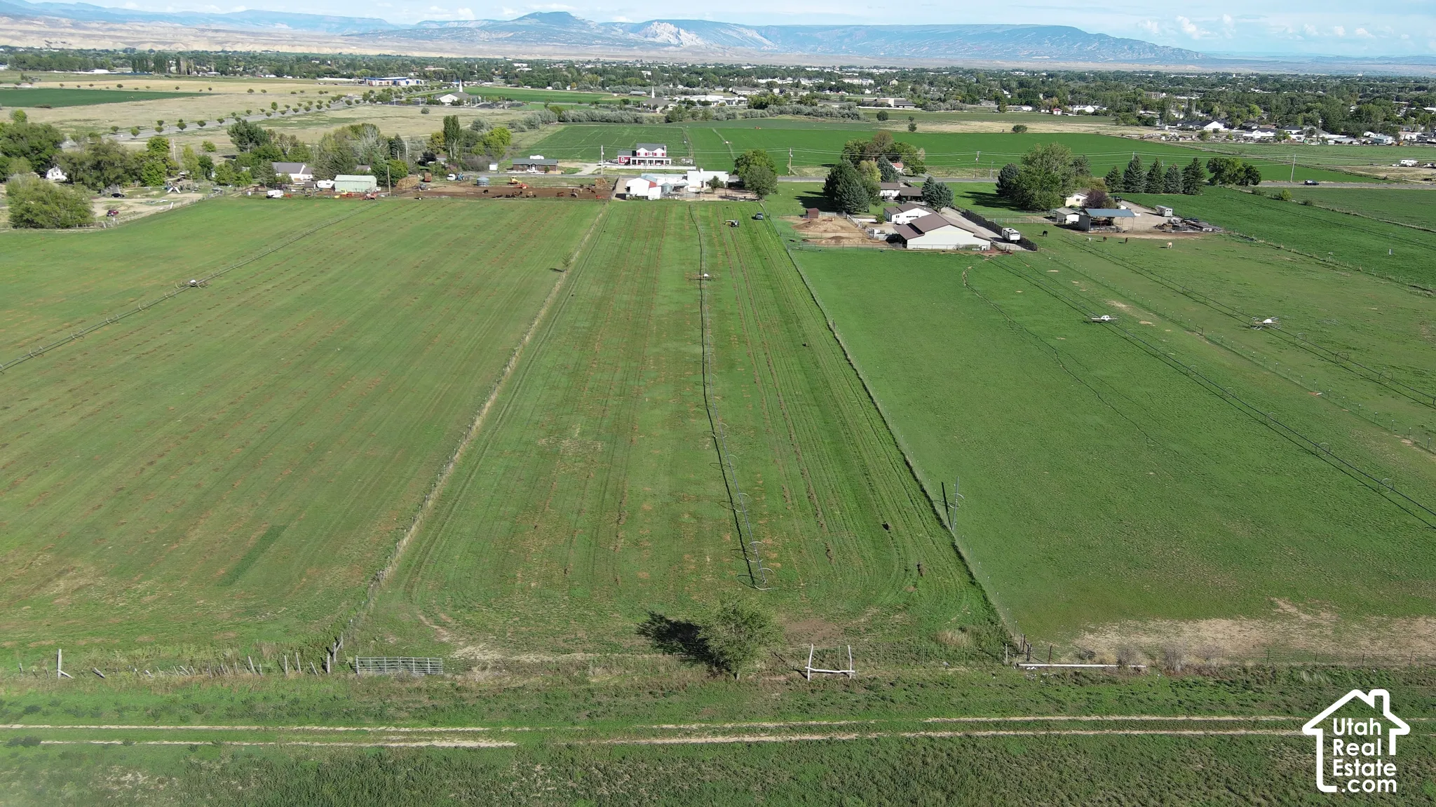 Expansive green fields with distant structures, showcasing a rural setting