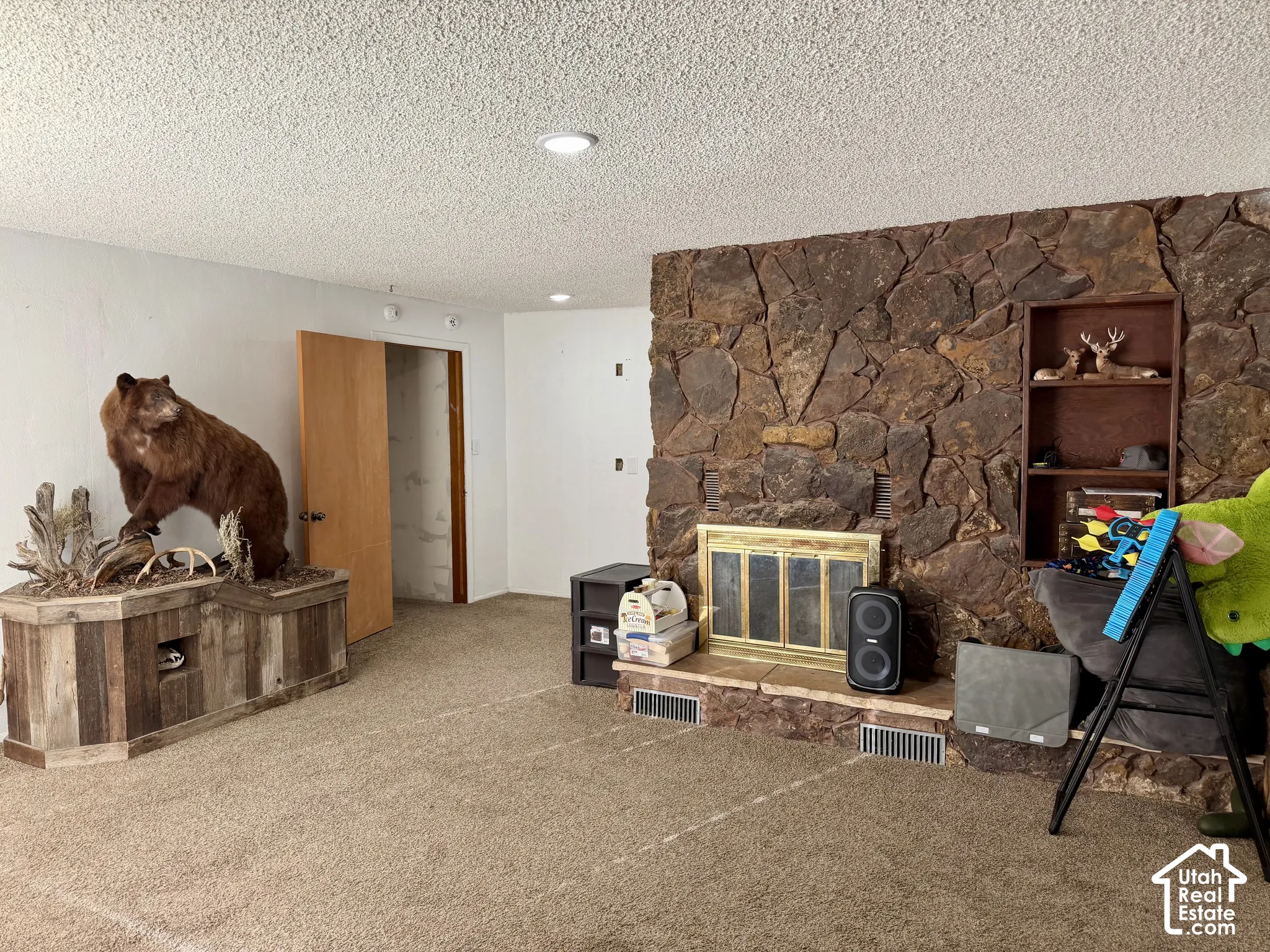 Stone-faced fireplace with a brass-finish insert and built-in shelving