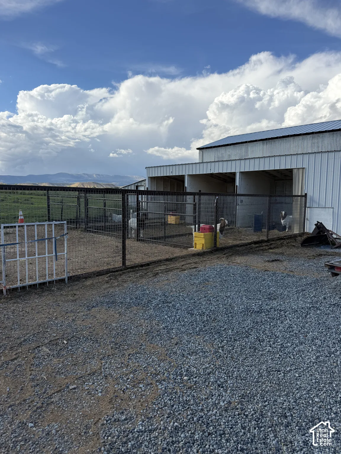 Gravel surface, metal fencing, and an outbuilding with a metal roof