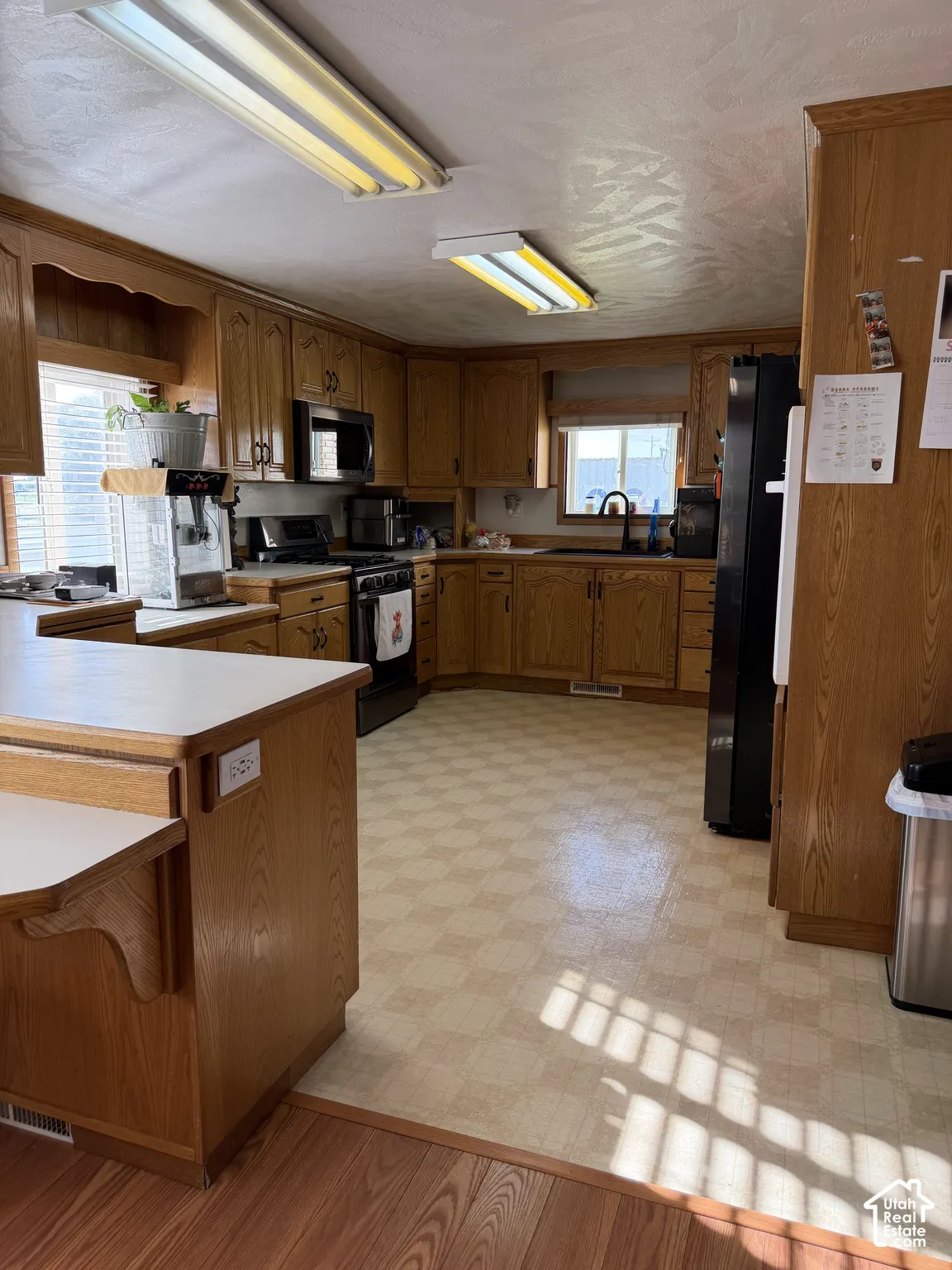 Kitchen featuring wood cabinetry, laminate countertops, vinyl flooring, and integrated black appliances