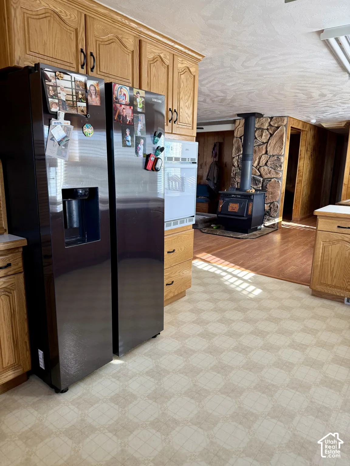 Wood cabinetry, built-in stainless steel appliances, wood-finish flooring, and a stone-clad wood-burning stove