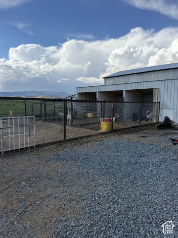 Gravel surface, metal fencing, and an outbuilding with a metal roof