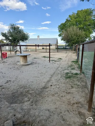 Fenced outdoor area with a gravel surface, featuring a built-in play structure