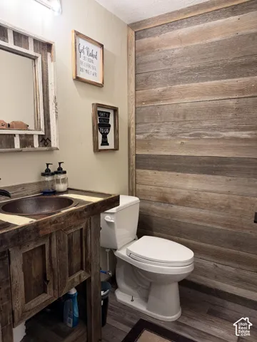 Distressed wood-finish vanity with an integrated basin sink, white toilet, and wood-finish accent wall