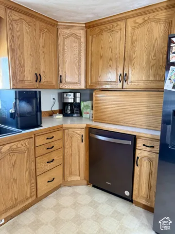 Oak cabinetry with decorative paneling, light-toned countertops, and an integrated dishwasher